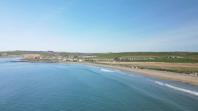 A aerial footage, following long sandy beach with gentile waves on a sunny day in Ireland