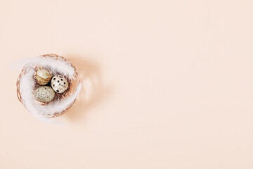 Quail eggs in basket on beige background. Flat lay, top view, copy space