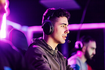Portrait of a young gamer playing video games online in dark gaming room with neon lights. © Dusan Petkovic