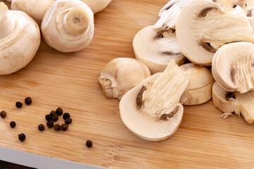 close up of whole and cut raw mushroom on wooden board