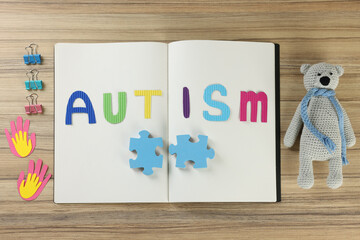 Flat lay composition of notebook with word Autism, clips and toys on wooden table