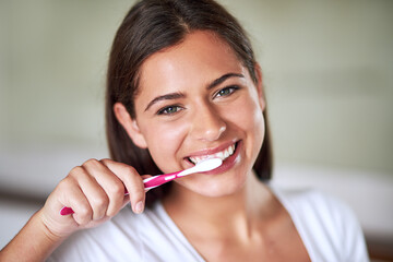 Minty fresh. Portrait of a beautiful woman brushing her teeth in the bathroom at home.