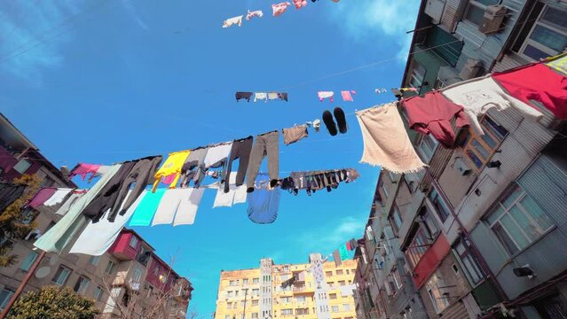 Laundry hung on clotheslines between apartment buildings. Sunny weather, humid climate and blue sky. Old dilapidated houses in a dangerous area. Historical buildings. Favela. Georgia Batumi.