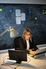 Skilled female financier analyzing financial data. Busy woman in glasses working till evening,...