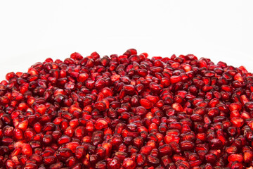 Red pomegranate fruit seeds close-up on a white background.