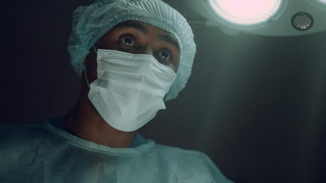 Focused surgeon performing surgical operation in intensive care unit portrait.