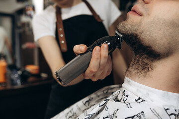 Man getting his beard trimmed with electric razor. shaving beard in a barbershop