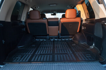 The big black empty trunk of SUV car with rubber mat and with leather folder on the floor Open luggage carrier of car closeup.