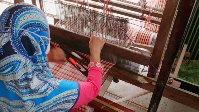 Home manufacture of fabrics and textiles, longyis, scarves. Utlized materials are silk, cotton and lotus  at Chau Doc city, An Giang province, Vietnam. Woman makes the traditional scarf.