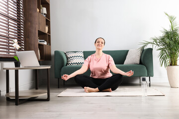 Fototapeta premium Overweight woman meditating on rug at home