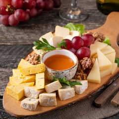 Cheese board with honey, walnuts and grape. Closeup