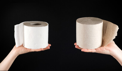 Two types of toilet paper in the hands of a person - white soft paper and gray from waste paper on a black background