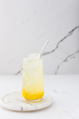 Refreshing drink with mango pulp in a glass on the background of a marble wall, cut mango next to the glass