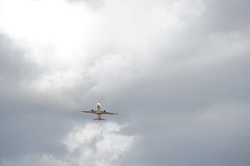 Fototapeta na wymiar Plane is flying in white-grey clouds