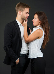 sexy man and woman in business look on black background, couple