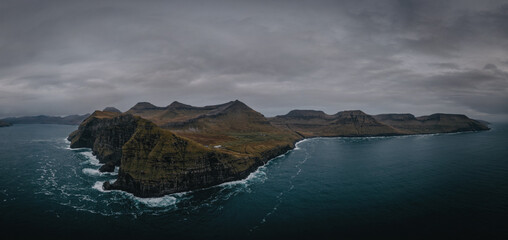 Fototapeta na wymiar Flying a drone high above the Atlantic Ocean to capture the enormous cliffs of the Faroe Islands at Nordradalur. Streymoy island, november 2021. Panoramic view