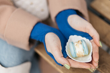 Photo of macaroons. Girl holding macaroni in her hands. Macaroons in the color of the flag of Ukraine.