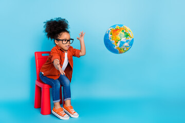 Photo of little girl playing with geography planet globe throwing in away fool around isolated on...