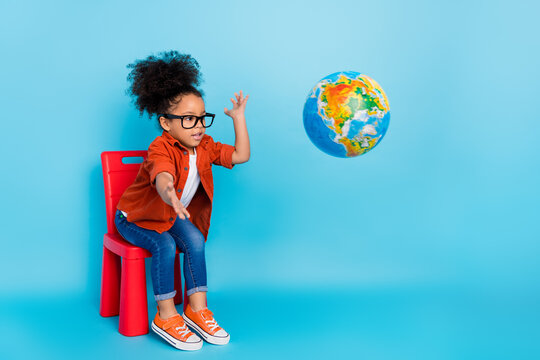 Photo of little girl playing with geography planet globe throwing in away fool around isolated on blue color background