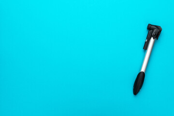 Bicycle pump over turquoise blue background with copy space. Top down flat lay photo of compact bike pump.