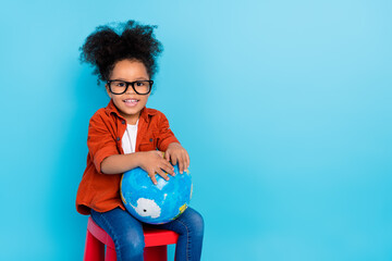 Photo of cute pretty little girl sitting small chair during lesson studying our planet isolated on blue color background