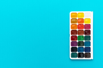 Minimalist photo of watercolor palette on turquoise blue background. Set of watercolor paint with...