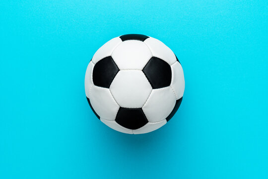 Top view photo of white and black soccer ball as football concept . Minimalist flat lay image of leather football ball over blue turquoise background with copy space and right side composition.