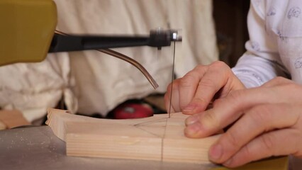 A woman saws handmade wooden products and toys with a working tool