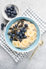 Oatmeal bowl with blueberries, banana slices and pumpkin seeds. Top view. Healthy breakfast food for diet, weight loss, clean eating