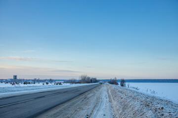 Winter evening landscape, road in the foreground. Sunset sky over the horizon.