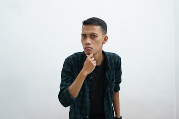 Portrait of young Asian man wearing dark green casual wear looking at camera with suspicious...