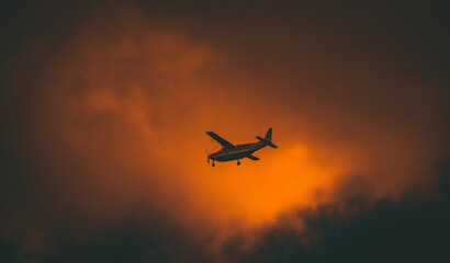Small aircraft flying into a fiery sunset