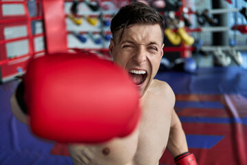 Young athlete fitness man with boxing gloves doing kick boxing training in sport gym.