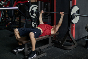 Fototapeta na wymiar A man lifting weights on a bench press.