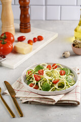 Keto paleo low-carb zoodles: zucchini noodles with parmesan cheese, cherry tomatoes, quil eggs on light grey surface