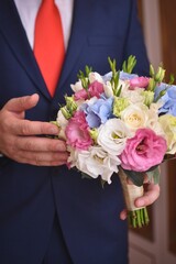 A beautiful wedding bouquet of flowers in the hands of the groom. Vertical photo. Wedding. Wedding bouquet.