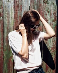 Fototapeta premium girl on a sunny day posing near a wooden wall