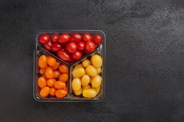 Red, yellow and orange cherry tomatoes in a packing box