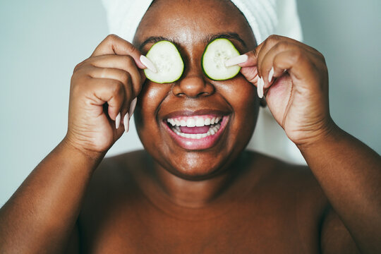 Young african girl having fun holding cucumber skin care therapy - Main focus on nose