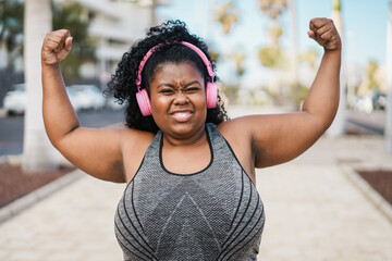 Happy curvy african woman doing workout routine outdoor - Focus on face