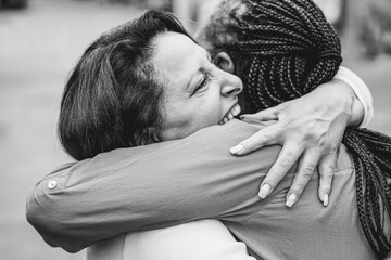 Senior multiracial women meeting and hugging each others outdoor - Focus on hand - Black and white...