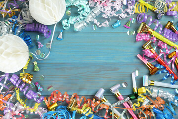 Frame of colorful serpentine streamers and other party accessories on light blue wooden background,...