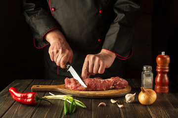 A professional chef cuts raw veal meat on a cutting board before baking. Asian cuisine. Cooking delicious food in the kitchen.