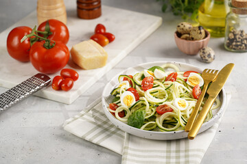Keto paleo low-carb zoodles: zucchini noodles with parmesan cheese, cherry tomatoes, quail eggs on...