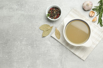 Bowl with delicious bone broth and ingredients on light grey table, flat lay. Space for text