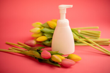 Mockup of beauty cosmetic makeup bottle product with skincare healthcare concept on pink background with tulips.
