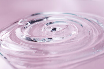 Sample of transparent shower gel on violet background, closeup