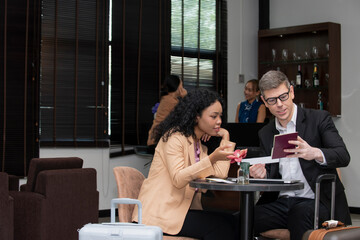 African woman with businesss man  passenger sitting in airport lounge waiting for flight landing