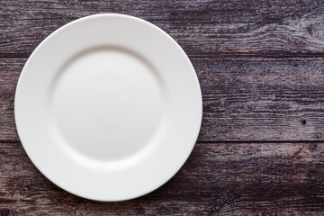 Plate on the background of a wooden tabletop. View from above. Small flat round white plate. Place for text.