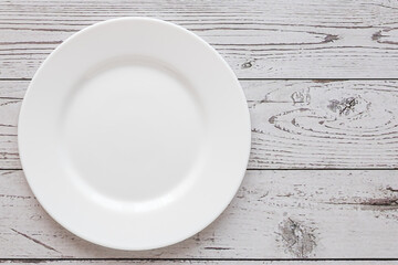 Plate on the background of a wooden tabletop. View from above. Small flat round white plate. Place for text.